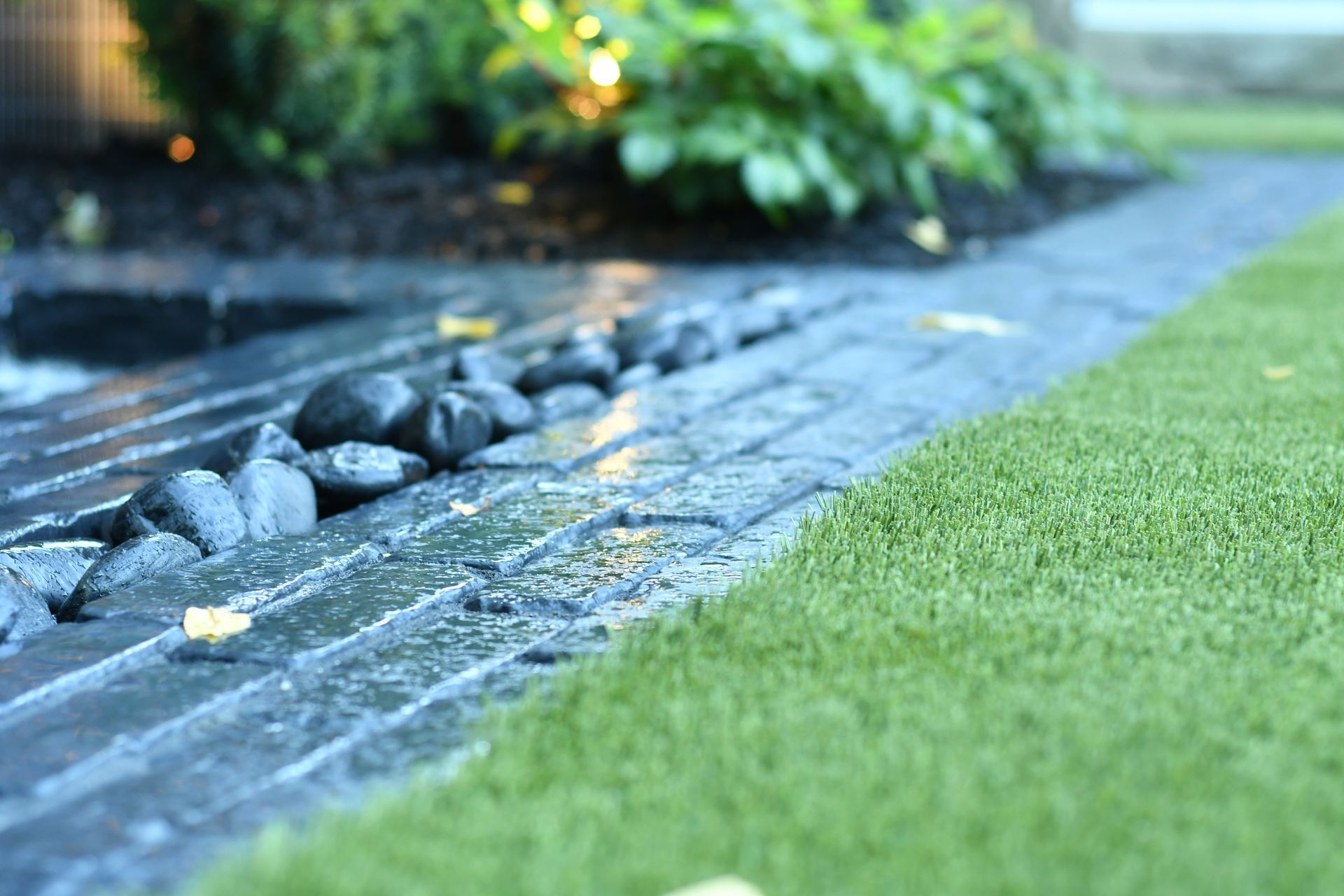 Wet stone pathway beside manicured green lawn